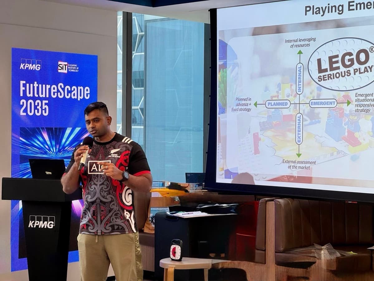 Prathap presenting with a microphone at a KPMG FutureScape session, the person behind the credentials at work